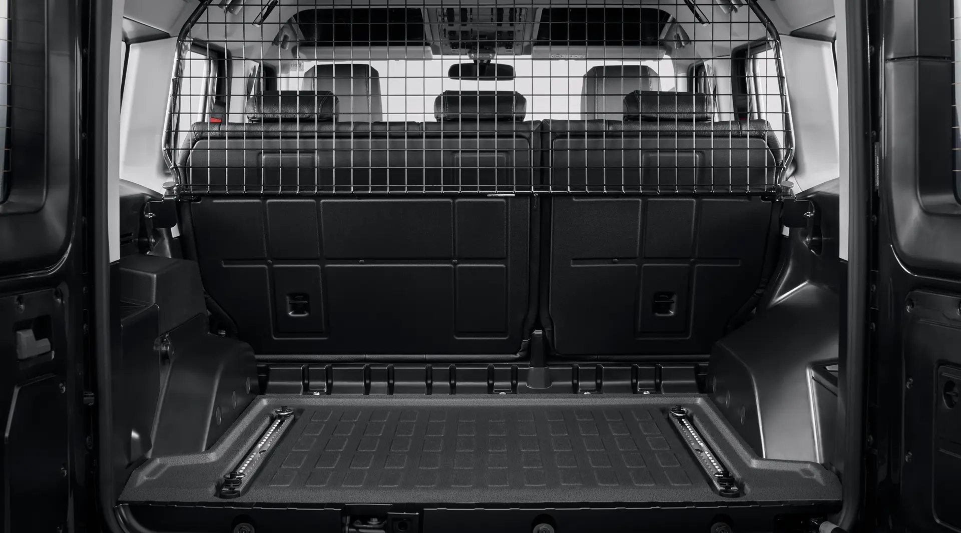 Rear load space of an INEOS Grenadier fitted with a mesh cargo barrier and a moulded load tray