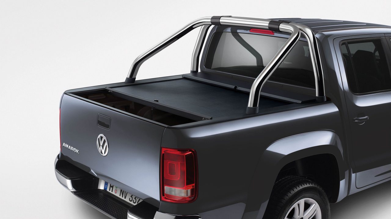 Rear three-quarter detail of a grey Volkswagen Amarok fitted with a roll cover and a polished stainless sports bar